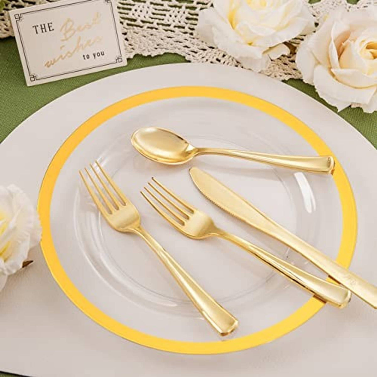 Gold-rim white dinner plate with gold spoon and fork on clear tabletop