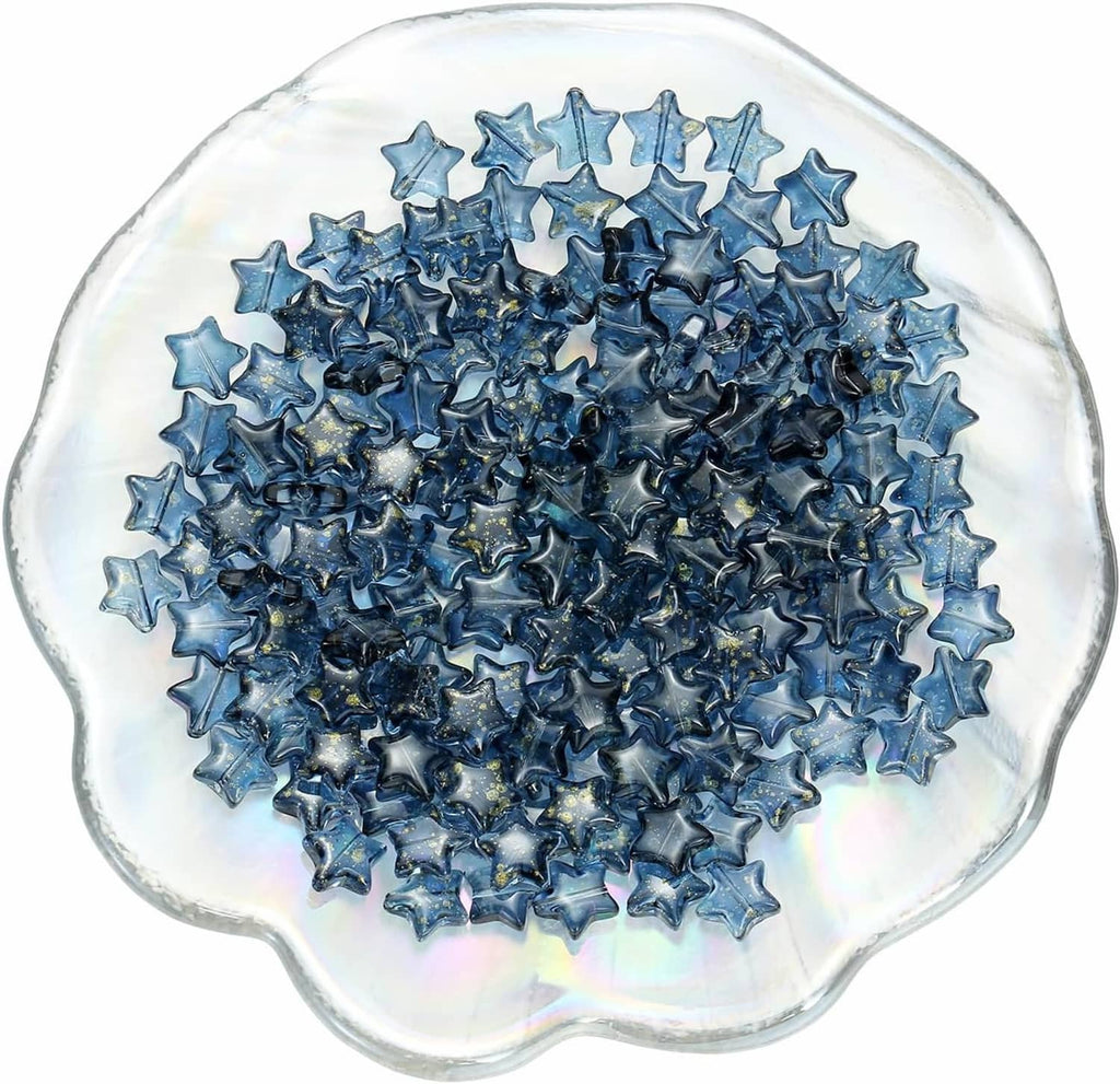 Dark blue star glass spacer beads in a clear bowl, close-up