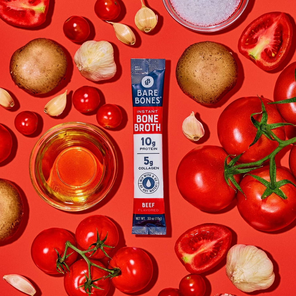 Instant bone broth powder stick packet among tomatoes, garlic, and mushrooms