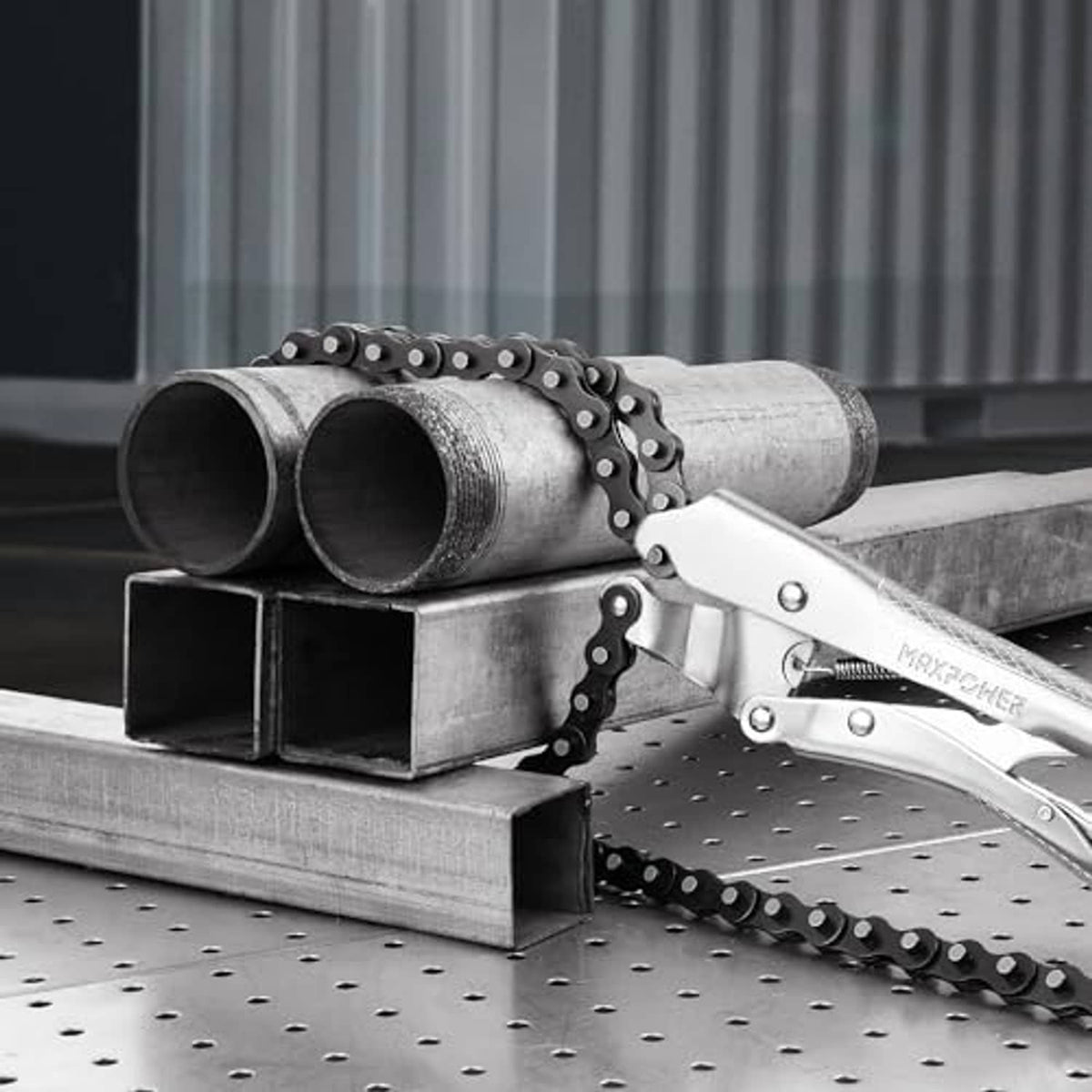Chain clamp pliers securing metal pipes on a perforated workbench with black chain