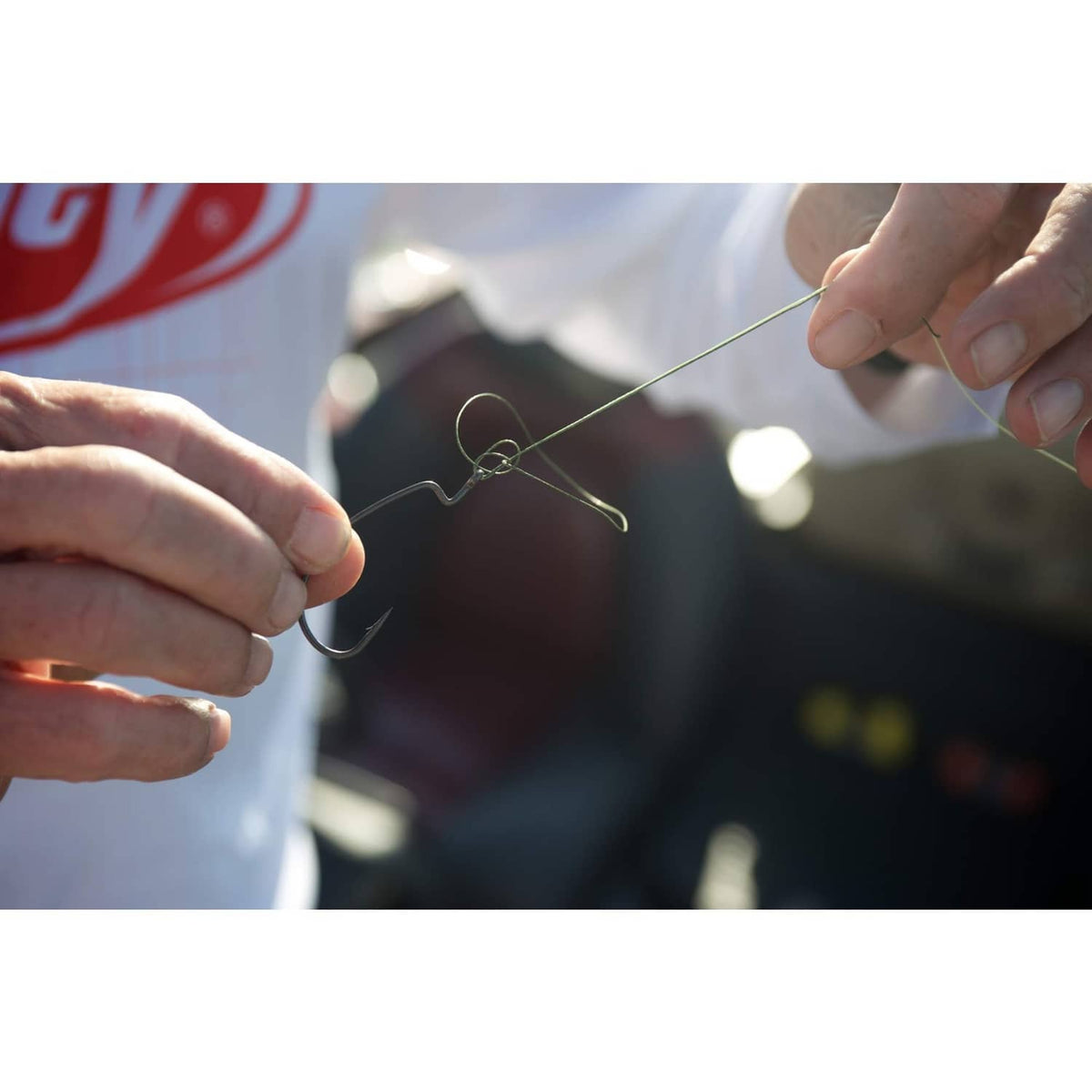 Hands tying a clear fishing line knot