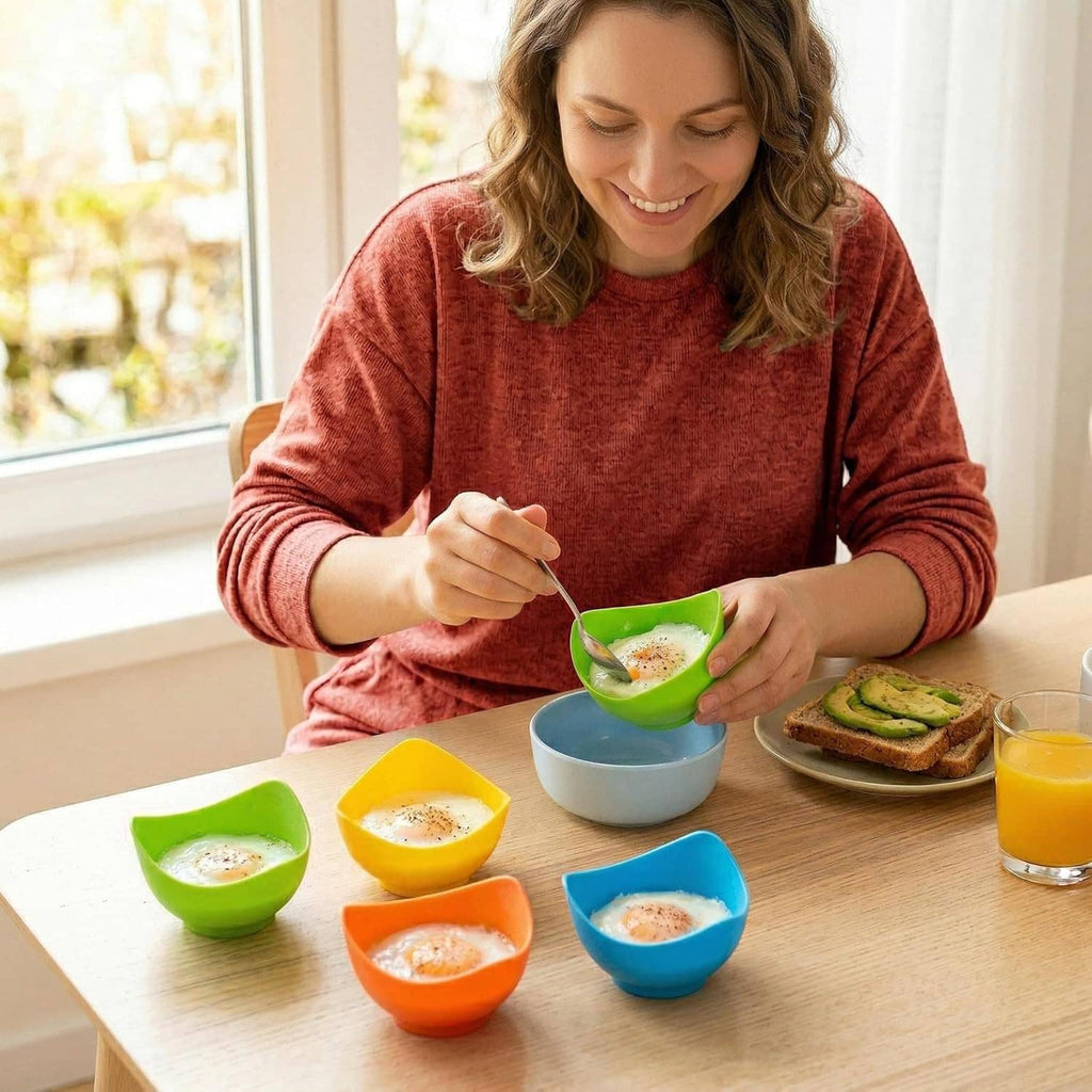 Colorful silicone egg poacher cups with poached eggs on a kitchen table