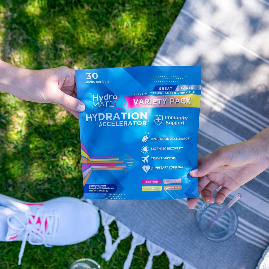 HydroMATE variety pack electrolyte pouches held by hands outdoors, blue pouch package