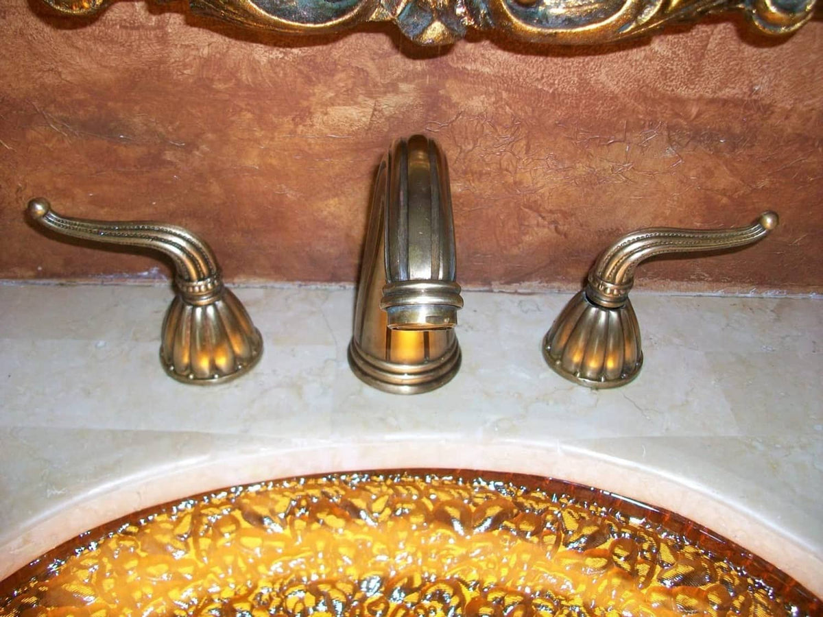 Brass-toned bathroom sink with three widespread faucets