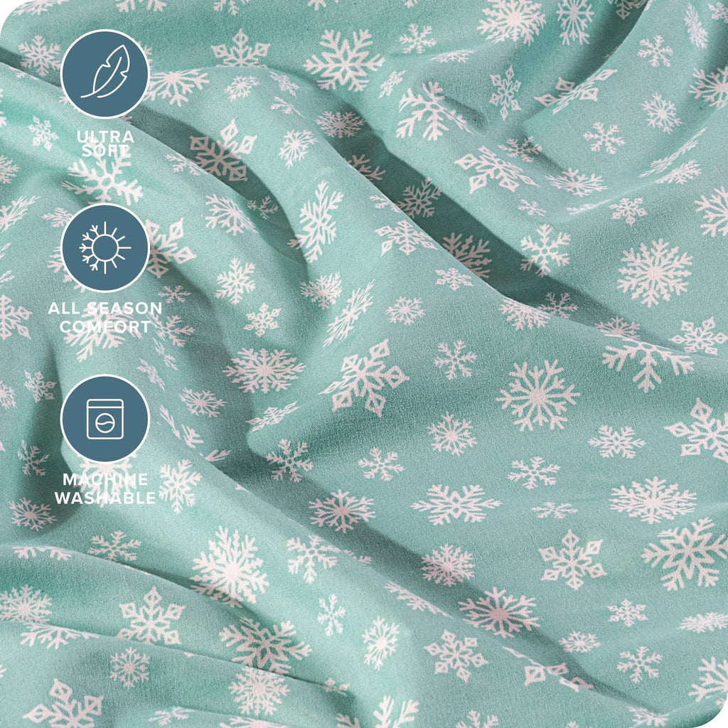 Teal bed sheet fabric with white snowflake print, soft drape close-up
