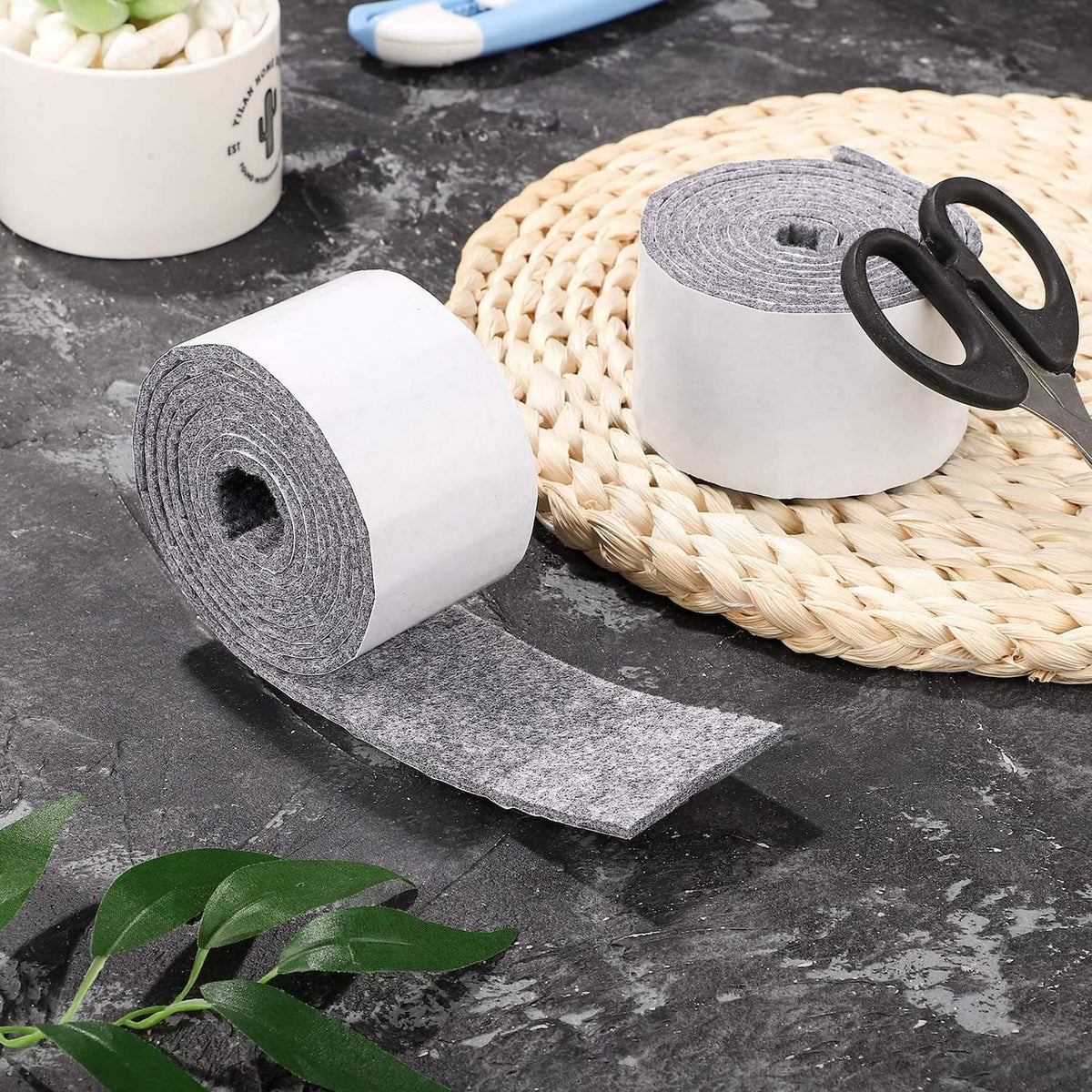 Light grey felt rolls with adhesive backing and loose felt strip on surface