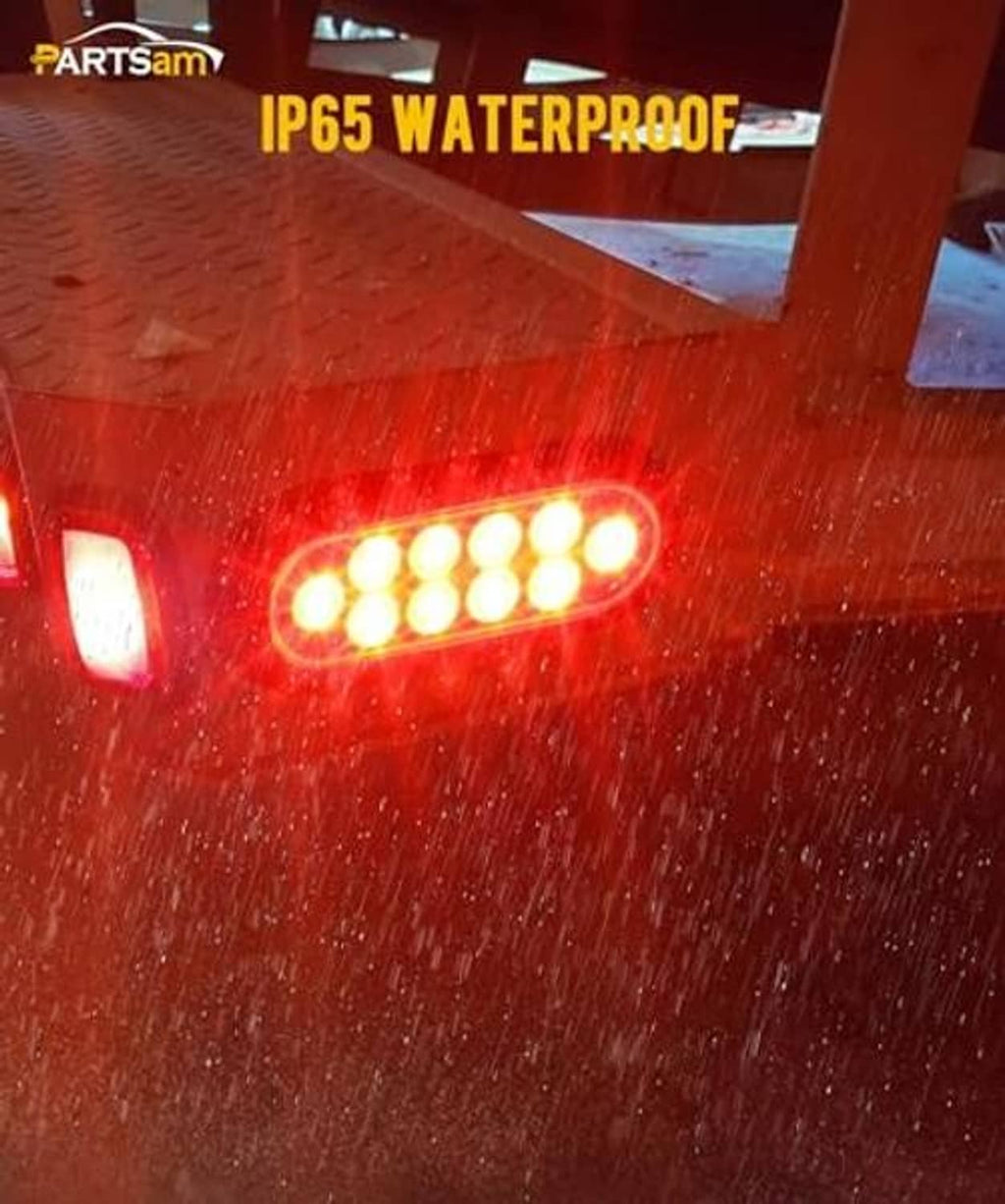 Oval red LED trailer tail light illuminated in wet conditions with raindrops