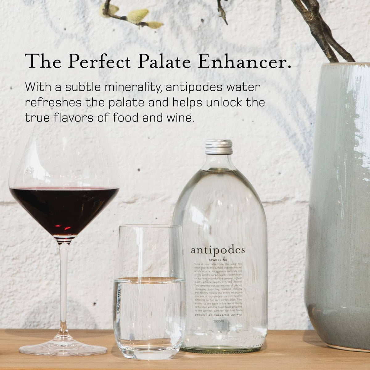 Antipodes sparkling water bottle with two glasses, clear glass and metal cap
