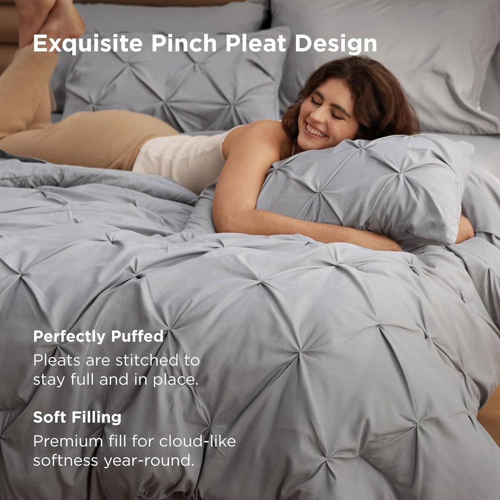 Grey pinch-pleat comforter set with soft filling, styled on a queen bed