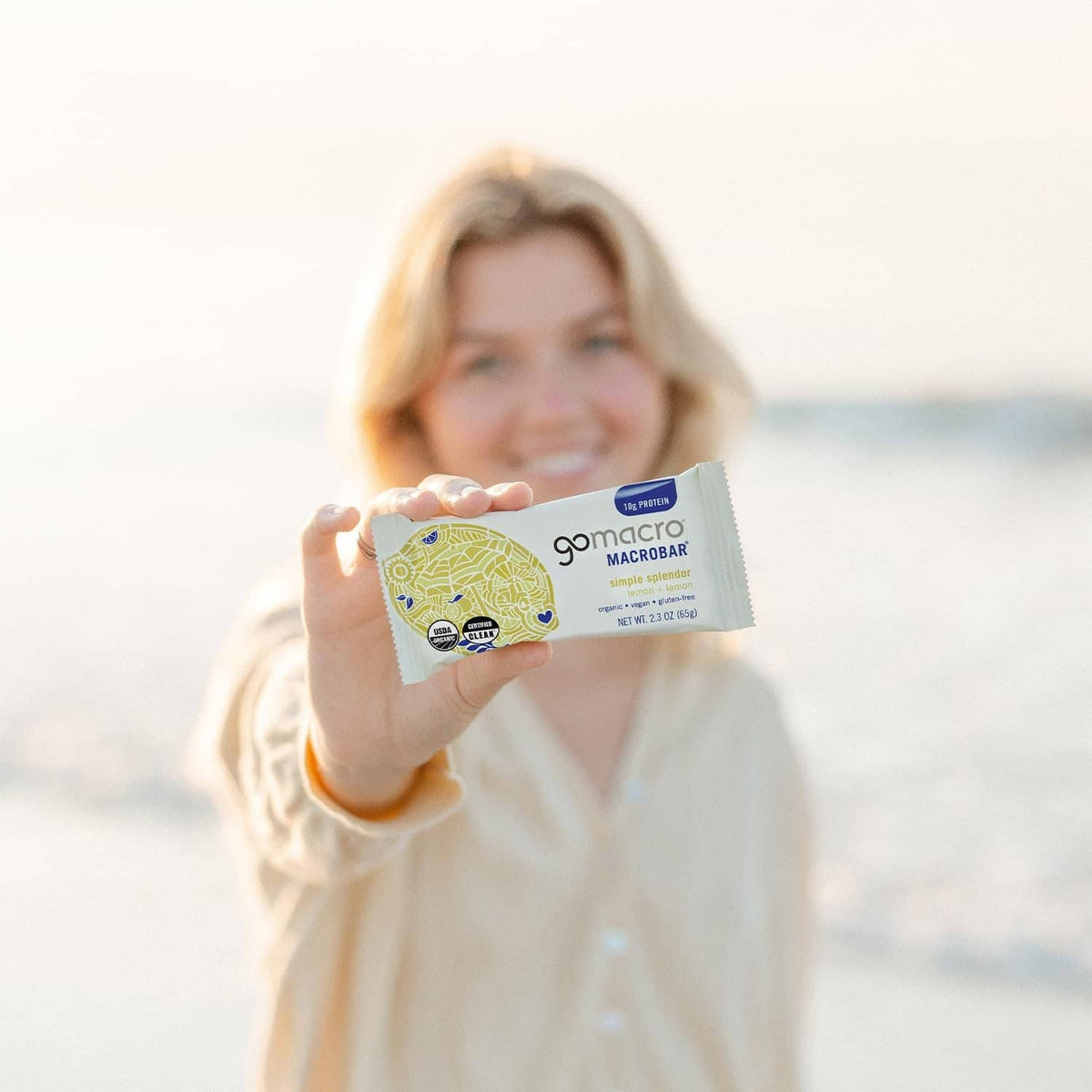 Organic lemon protein bar in a hand, showing Gomacro Macrobars wrapper