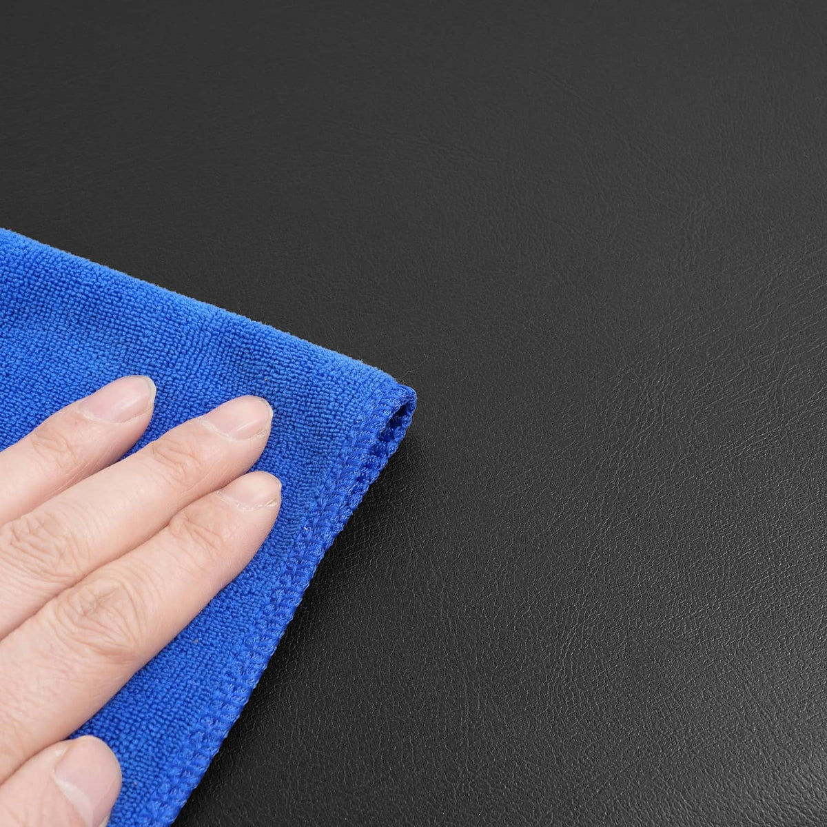 Blue microfiber cloth cleaning a dark surface