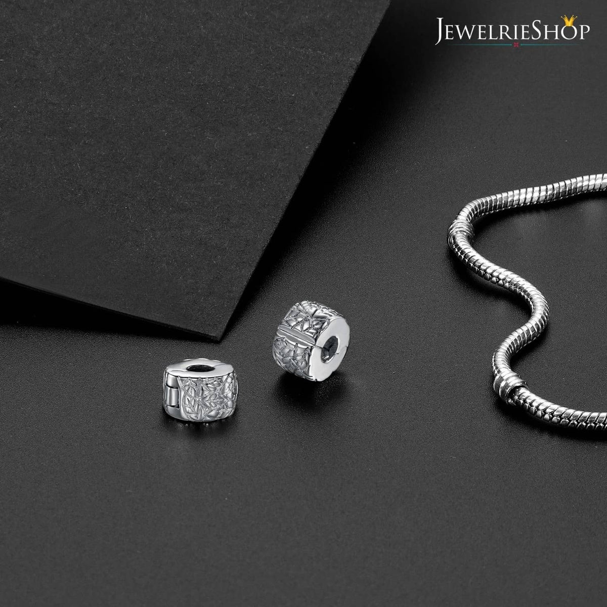 Silver round clip spacer charm bead with cutout pattern, displayed on bracelet