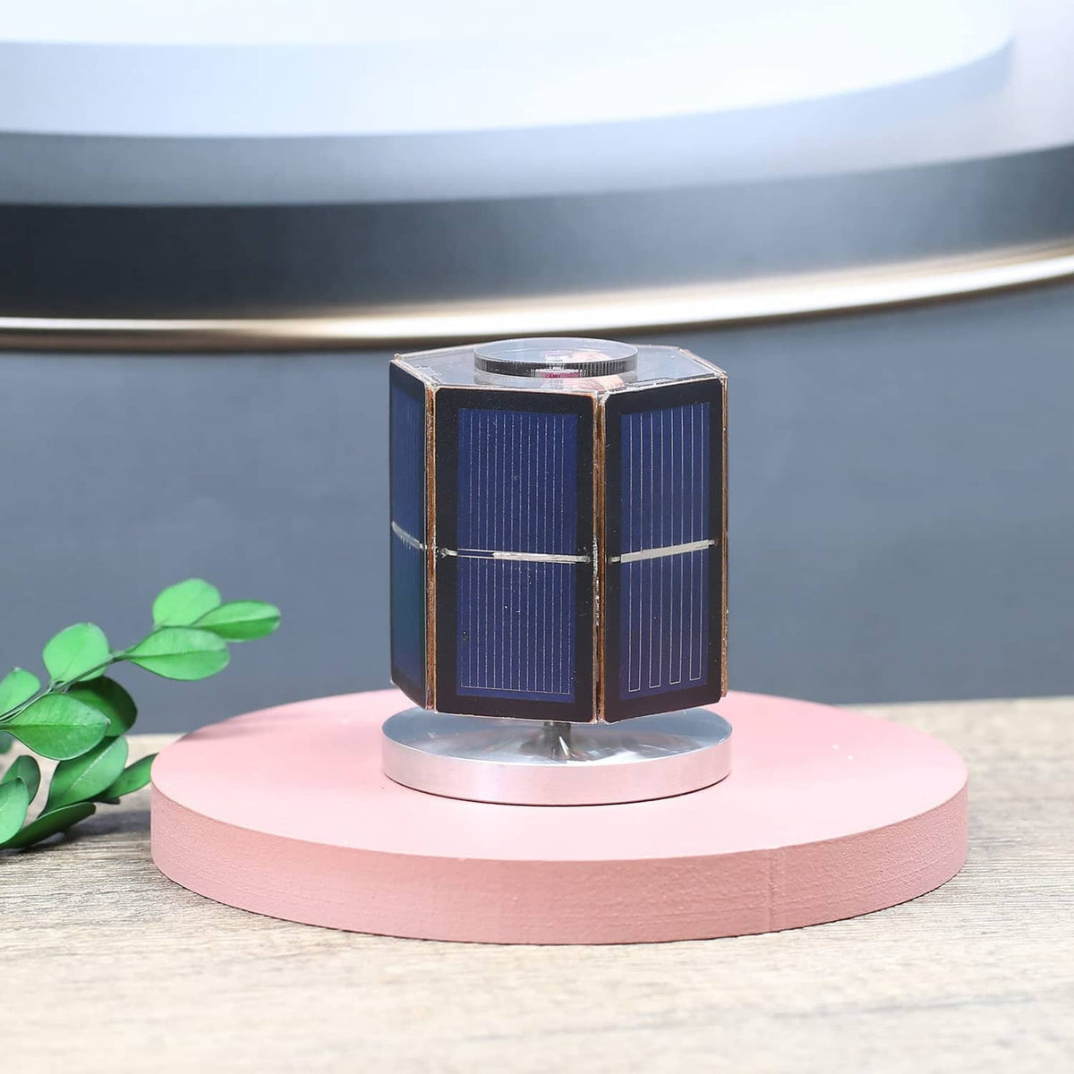 Solar motor toy with blue solar panel cube and central motor module on a round base