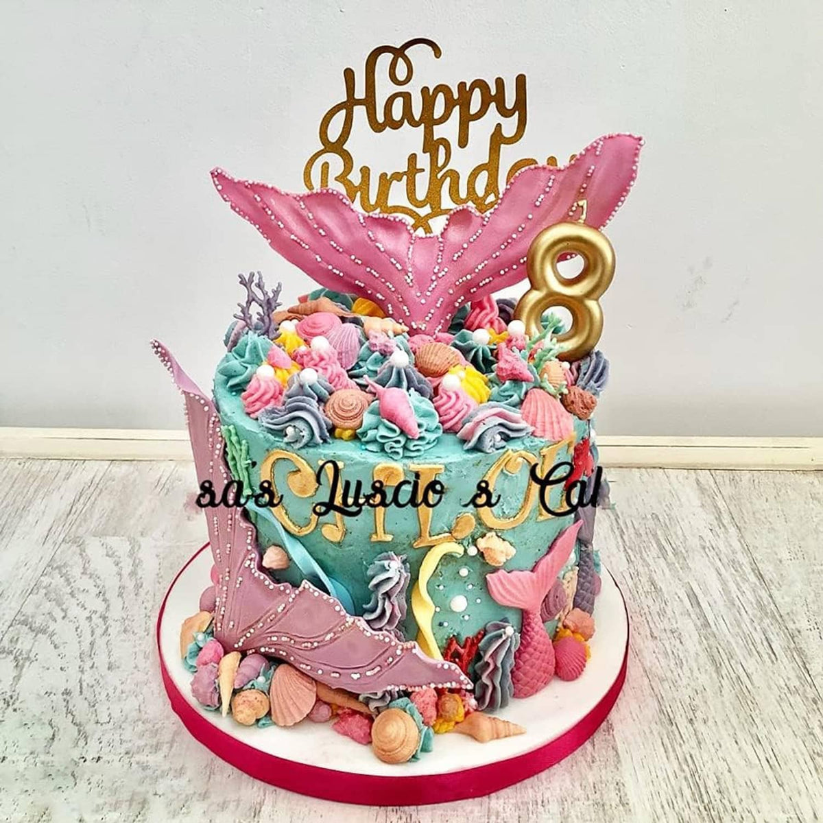 Marine-themed birthday cake with sea-animal decorations, colorful waves, and a gold number 8 topper