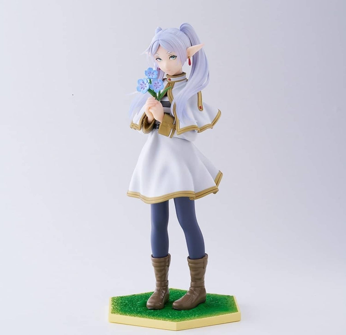 Character figurine in white dress with gold trim, bouquet in hand, green display base.