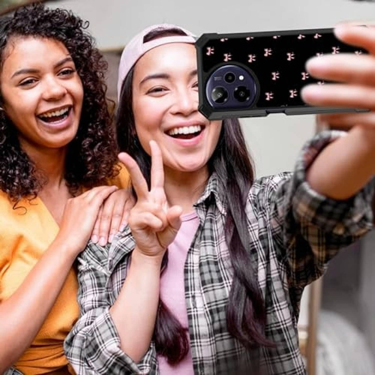 Phone case with pink bow pattern on a phone being taken with selfie, black case