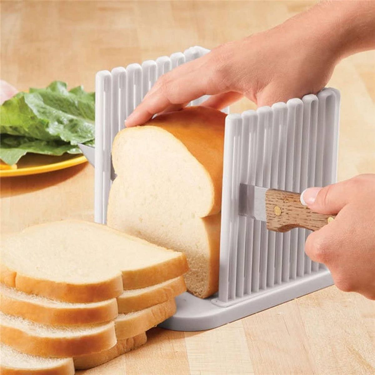 Hand holding a wooden blade in a white plastic bread slicing guide for even cuts