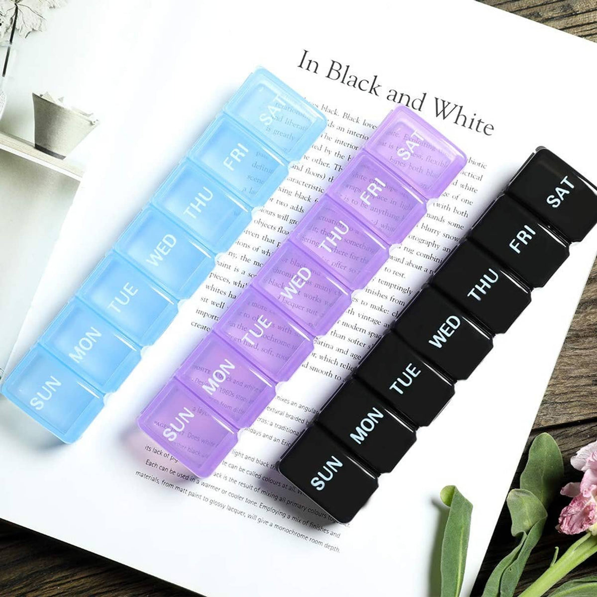 Two-pack weekly pill organizer set in black and white, day labels Mon–Fri and SAT
