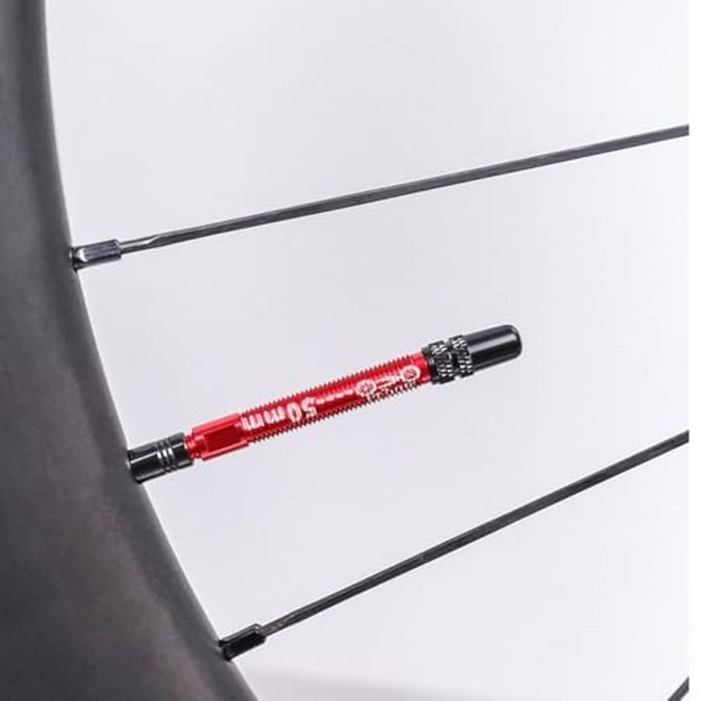 Red tubeless valve extension shown on a bicycle rim with threaded stem