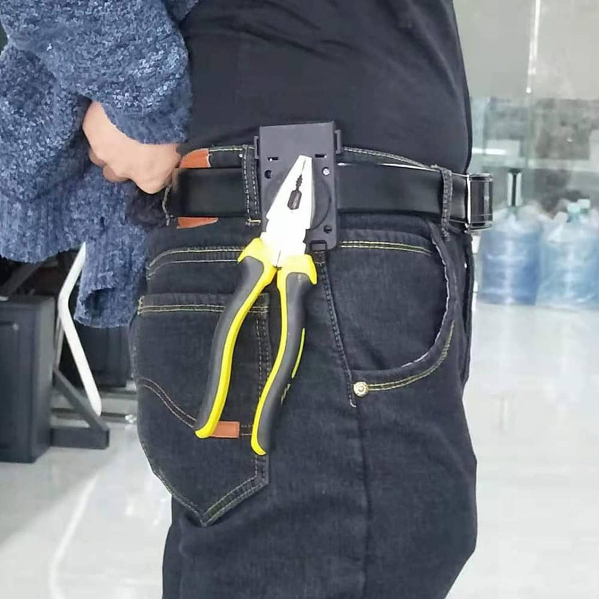 Magnetic belt holster clipped to jeans, holding a yellow-handled tool