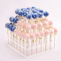 Three-tier clear cake pop holder stand with blue and pink cake pops on sticks