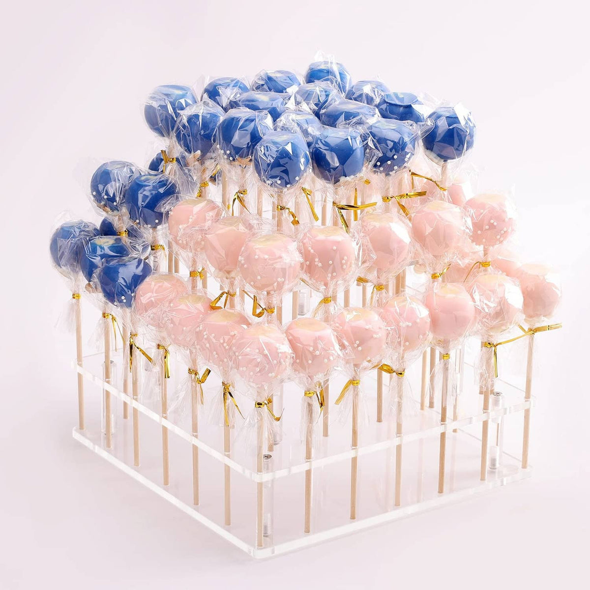 Three-tier clear cake pop holder stand with blue and pink cake pops on sticks