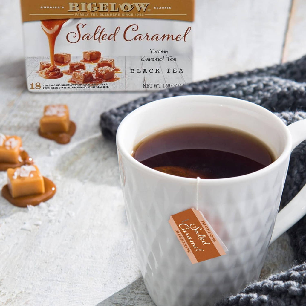 Cup of black tea with salted caramel tea bags and caramel pieces nearby