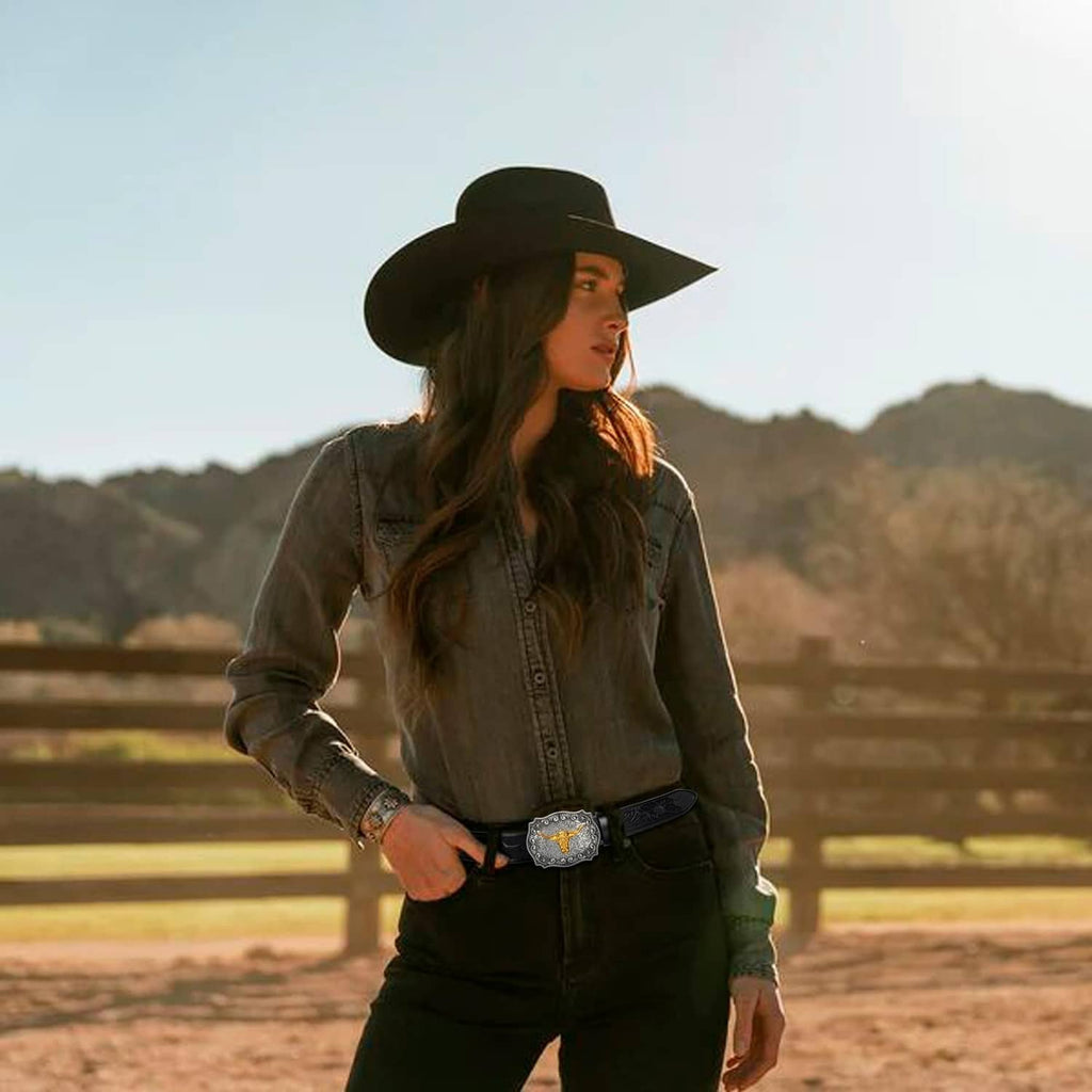 Western cowboy belt worn with dark outfit: black leather strap and silver buckle with gold bull
