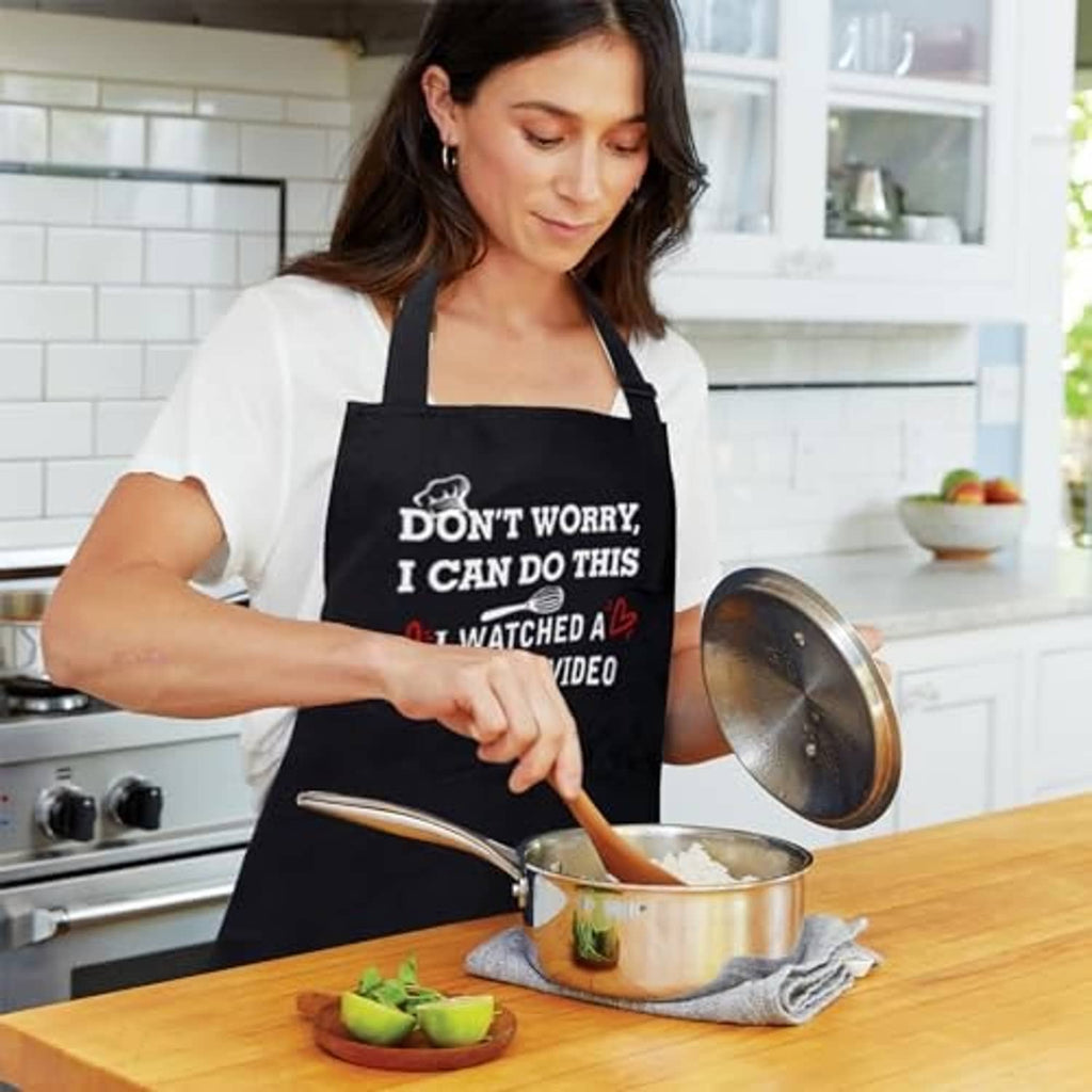 Woman wearing a black apron with "Don’t Worry, I Can Do This" slogan while cooking.