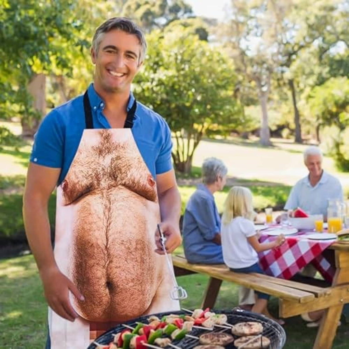 Funny novelty grilling apron worn at backyard cookout, printed male torso design