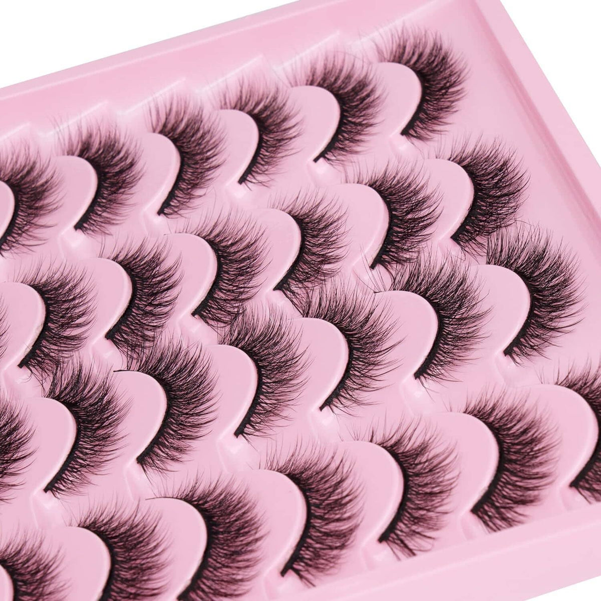 Close-up of dark cat-eye false lash bands in a pink tray, clustered