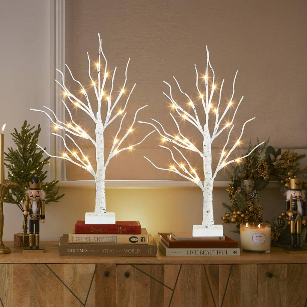Pair of white LED birch tree decorations with warm lights on square bases on a console