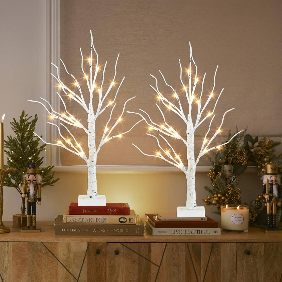 Pair of white LED birch tree decorations with warm lights on square bases on a console