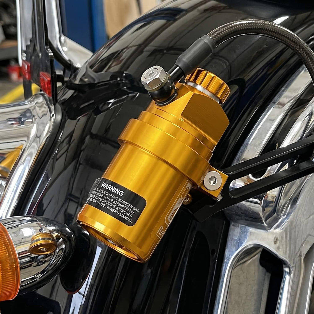 Gold rear shock reservoir with black mounting bracket and hydraulic hose connection