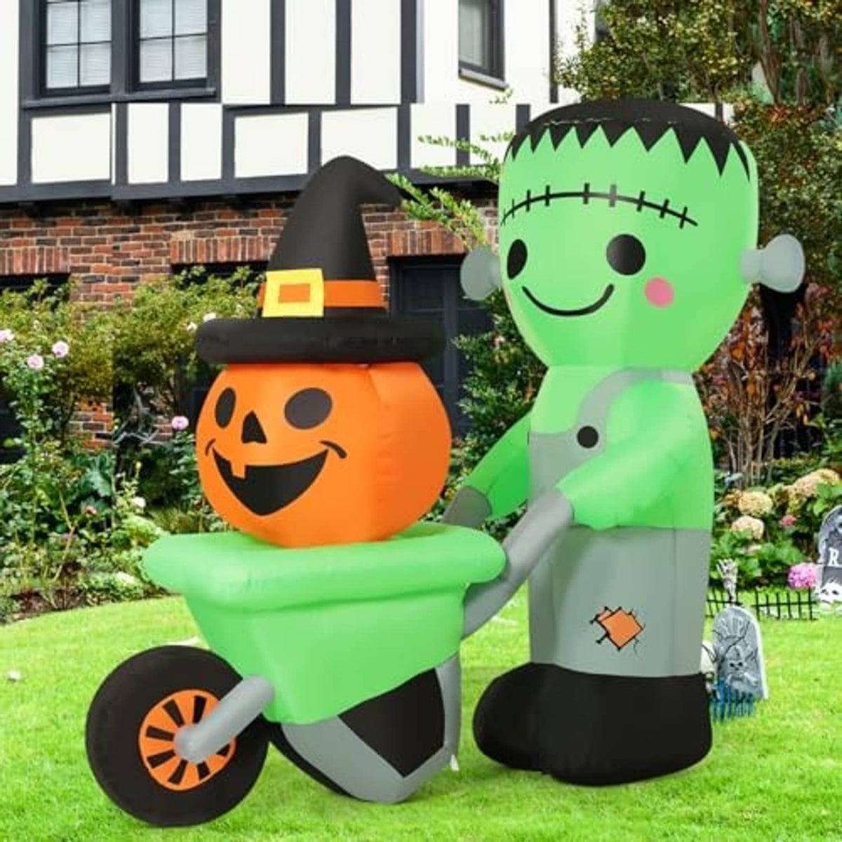 Green Frankenstein inflatable and orange pumpkin inflatable standing together with witch hat