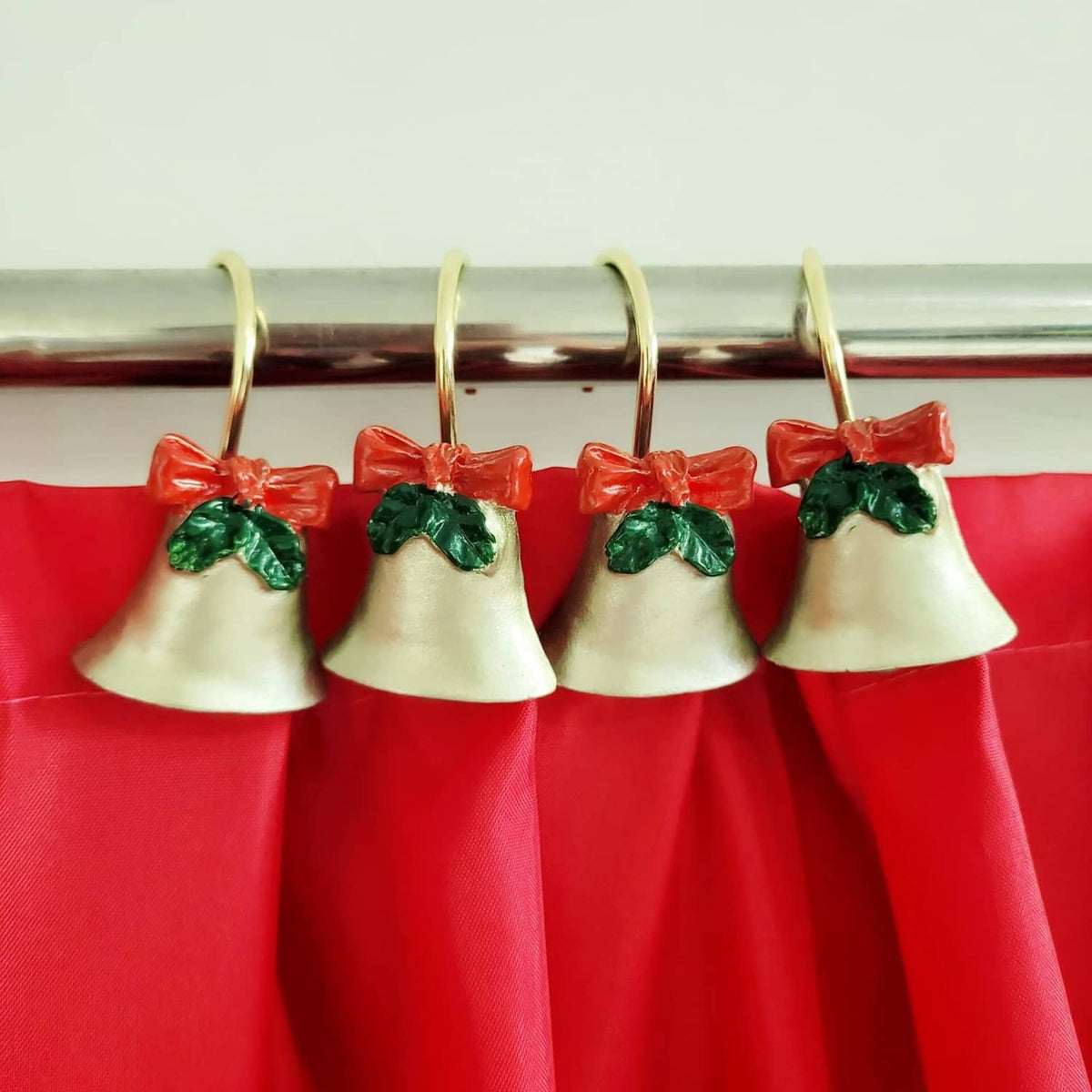 Red shower curtain top with four bell-like ornaments and greenery details on rings
