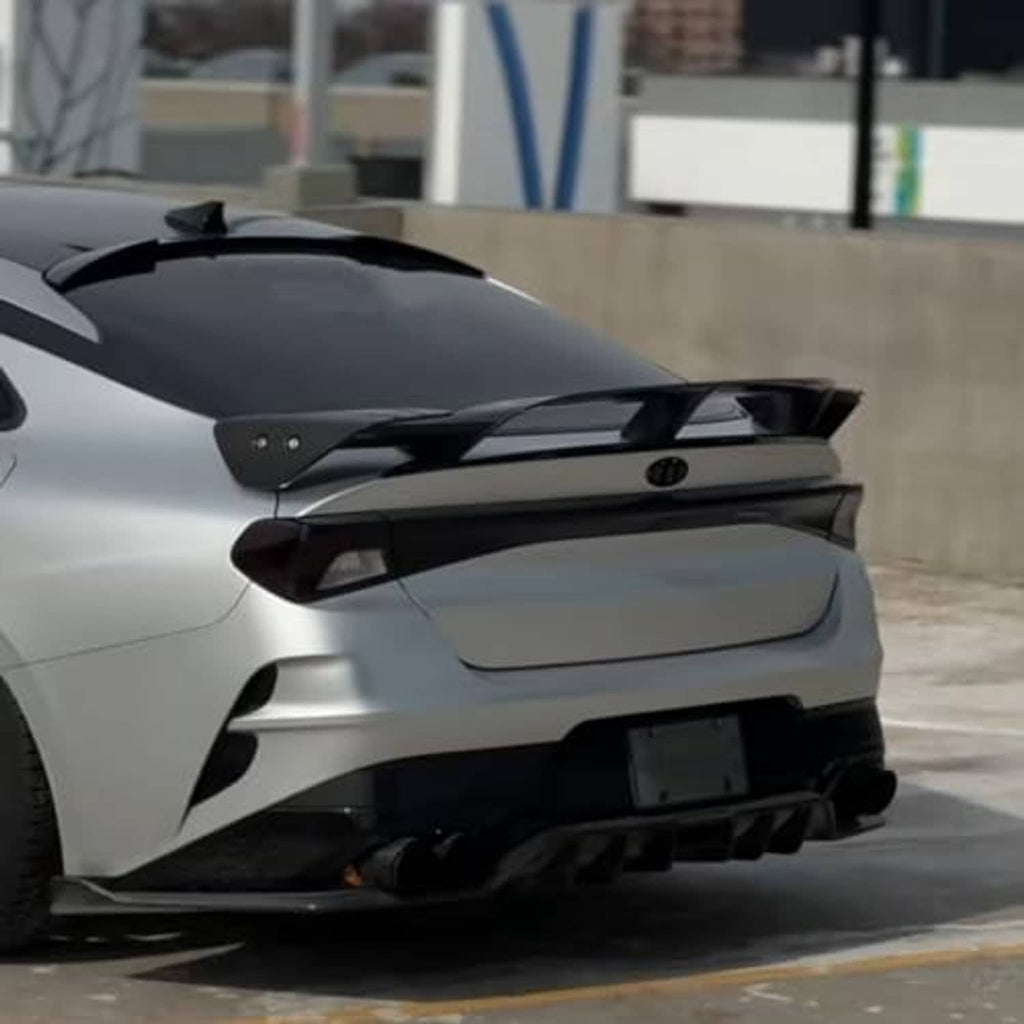 Black rear roof spoiler wing installed on the back of a white car.