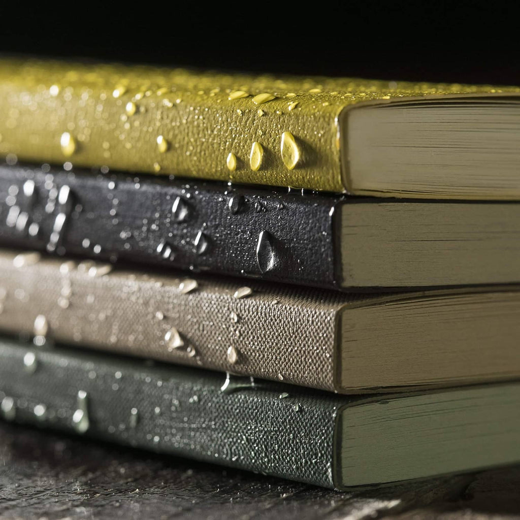 Weatherproof pocket notebooks stacked, textured covers with water droplets and close-up of spines
