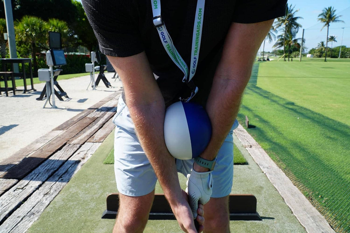 Compression ball golf trainer worn by golfer, blue-and-light gray ball with strap