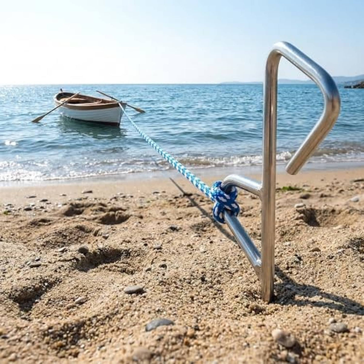 Chrome sand spike anchor with chain and blue rope line, standing in beach sand