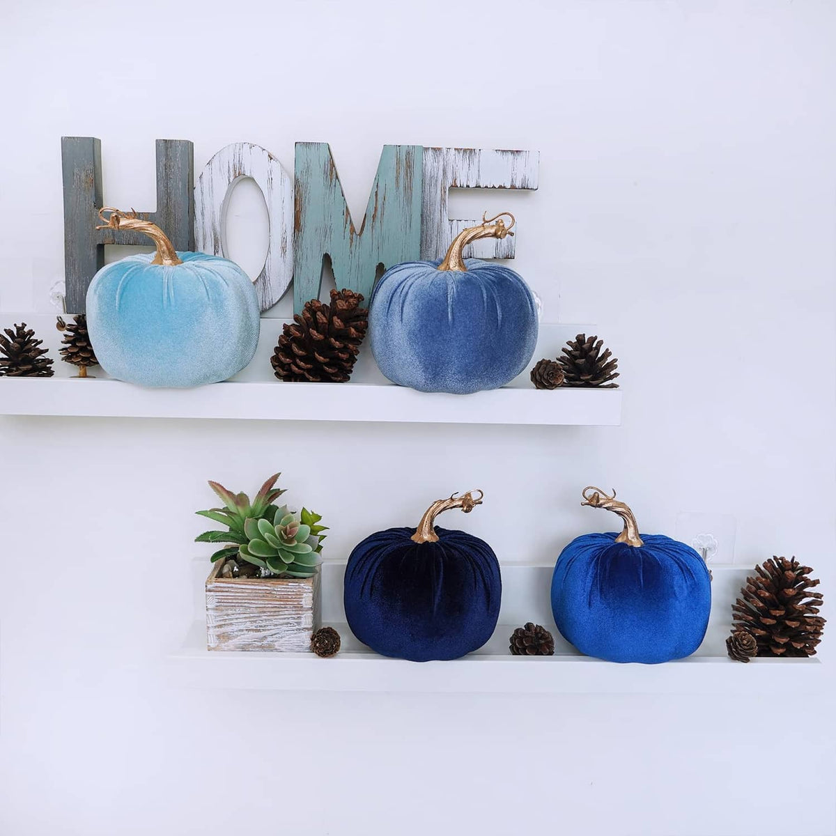 Blue faux velvet pumpkins with gold stems and hanging loops on wall shelves in mixed shades