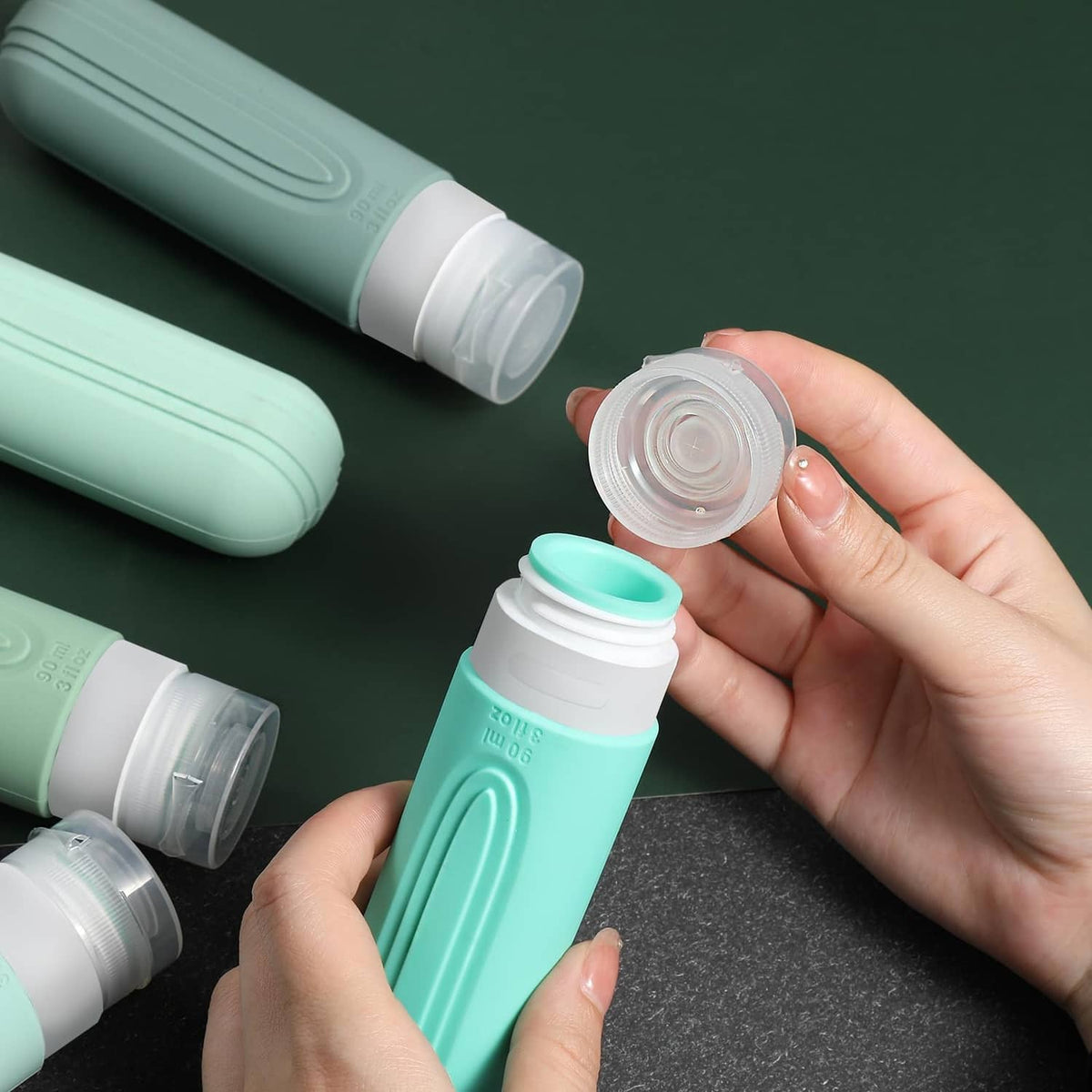 Mint green travel bottles with flip-top caps; hand holding an open screw lid