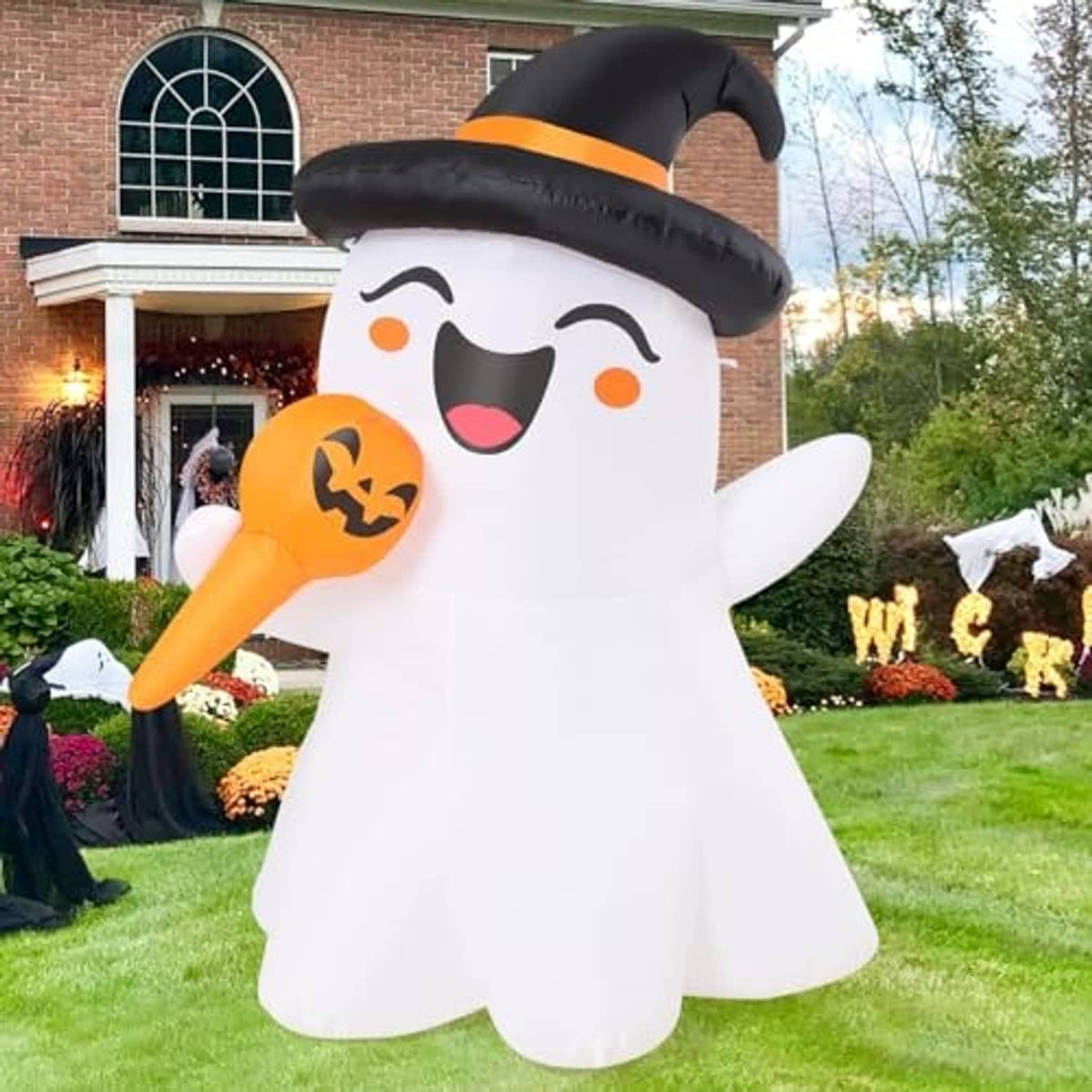 White inflatable ghost with black witch hat and orange jack-o-lantern, front view in yard
