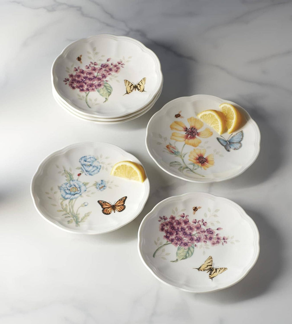 Six small round tidbit plates with lemon slice accents, butterflies, and flowers on white