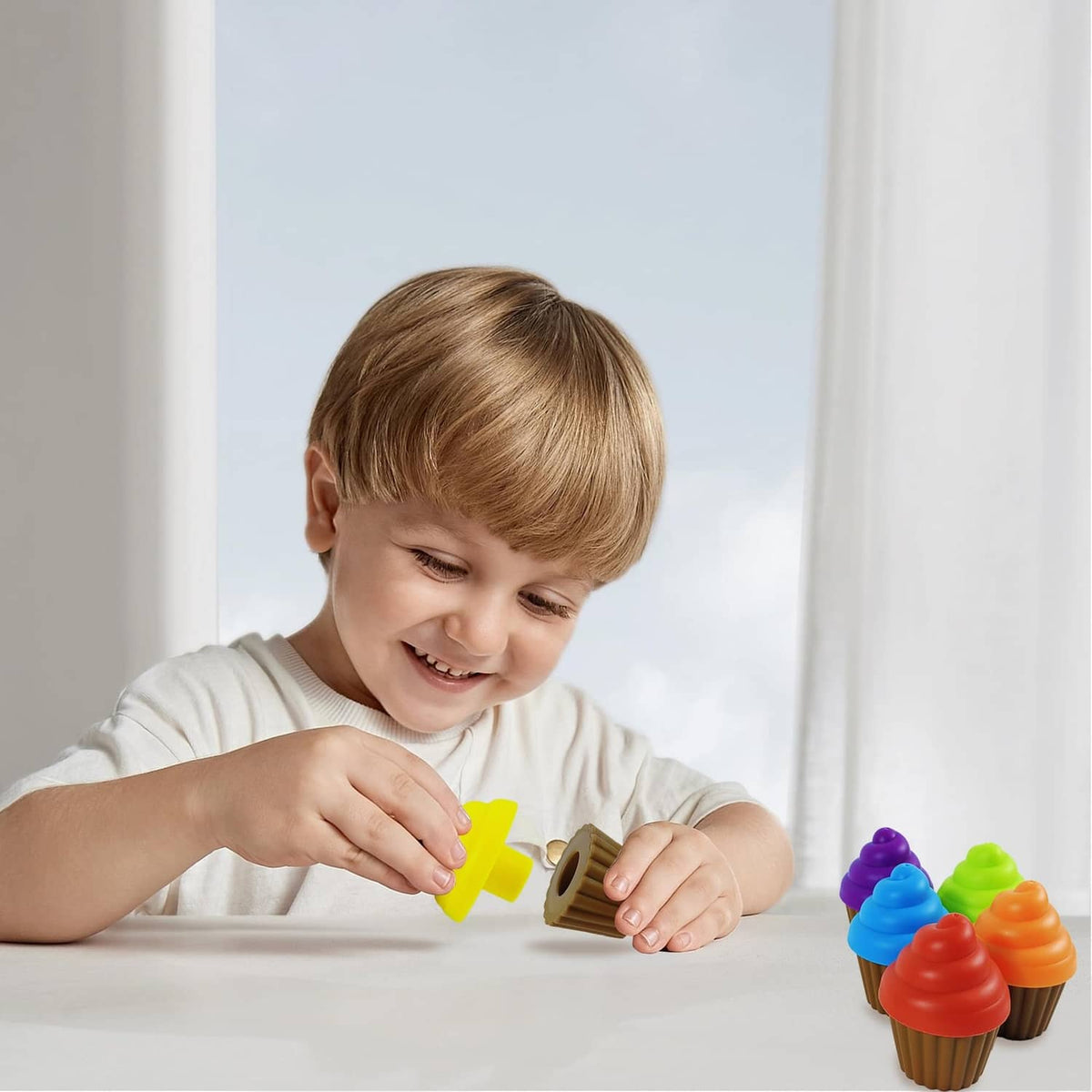 Young child holding a cupcake piece and playing with the rainbow tray set