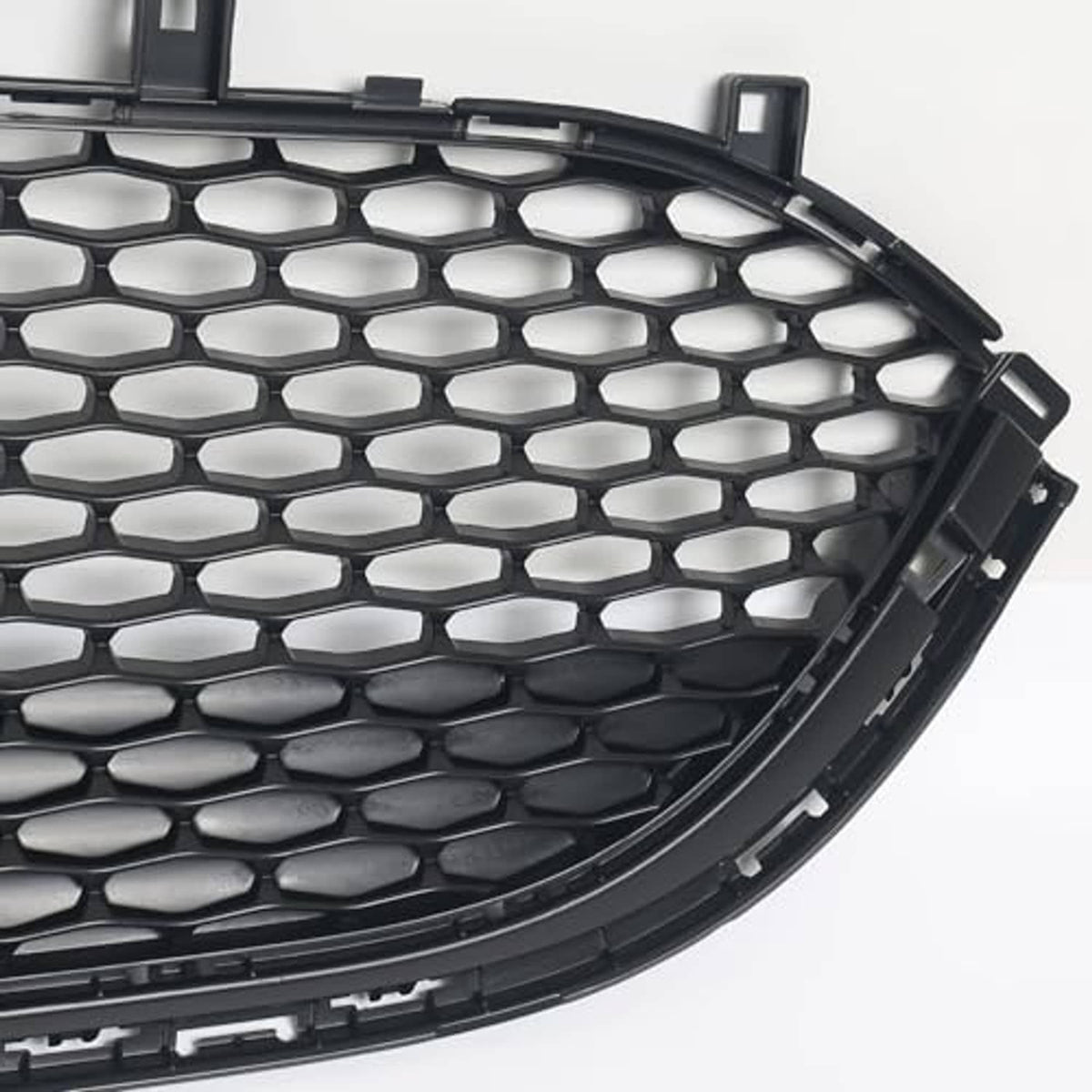 Corner view of front lower bumper grille with black honeycomb mesh and tabs.