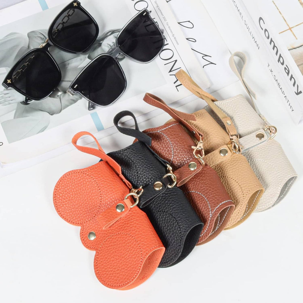 Assorted soft leather sunglasses bags with wrist straps and metal rings, black orange beige