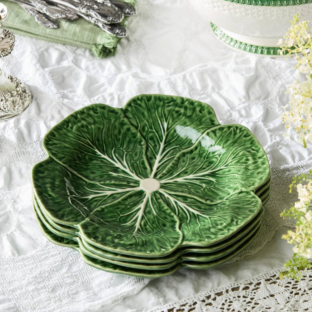 Set of four green cabbage-pattern dinner plates with white leaf-vein detail.