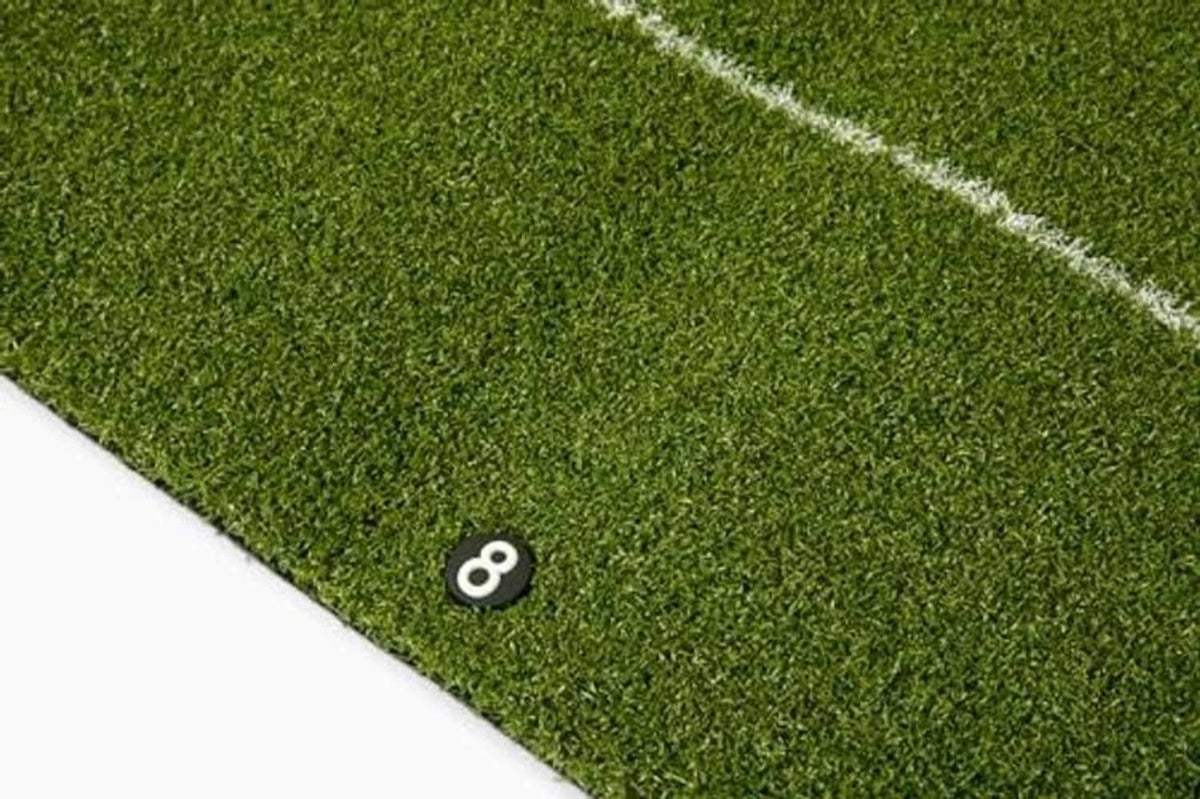 Green putting mat corner with numbered target marker and white boundary line
