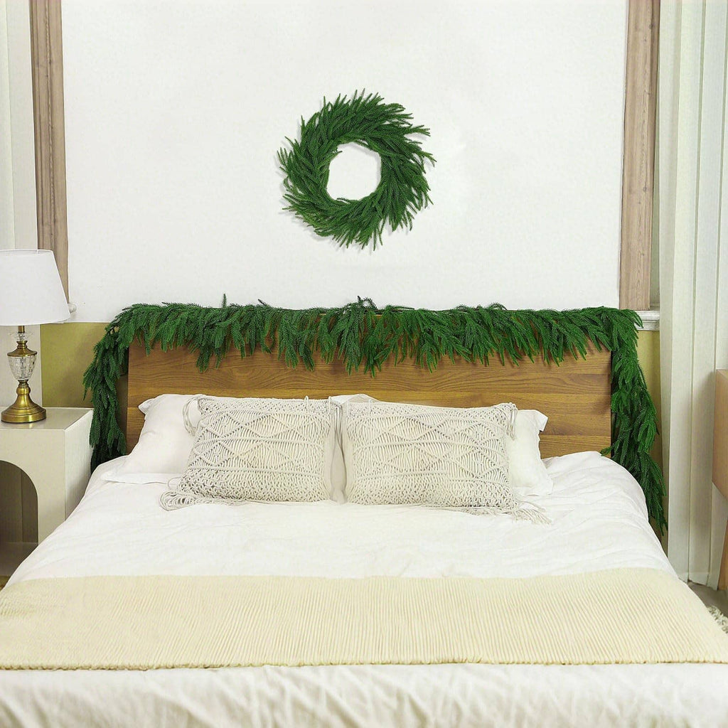 Green artificial pine garland border across a bed area, with a matching green wreath.